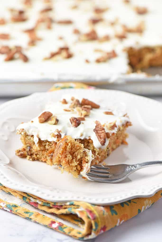 Bite of the best ever carrot cake sheet cake on a fork on white plate