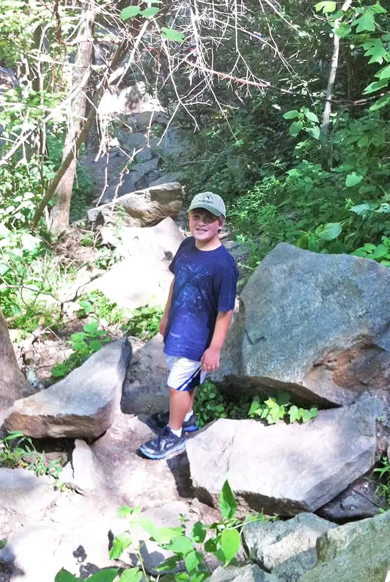 Boy climbing on rocks around Laurel Falls Trail in Smoky Mountains, Tennessee