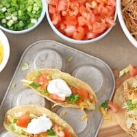 shredded chicken tacos with fresh ingredients on a muffin pan