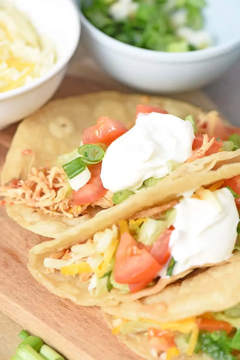 easy chicken tacos on a cutting board close up with fresh ingredients and sour cream