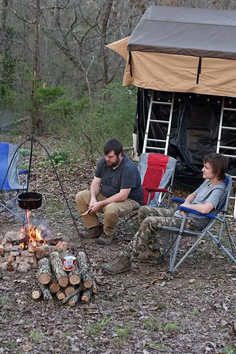 dad and son enjoying campfire cooking and rooftop tent camping