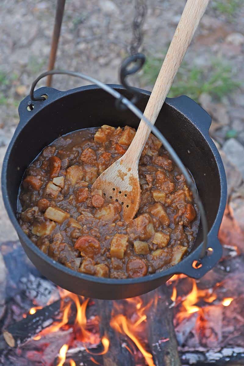 outdoor cooking over the campfire with beef stew in a Dutch oven