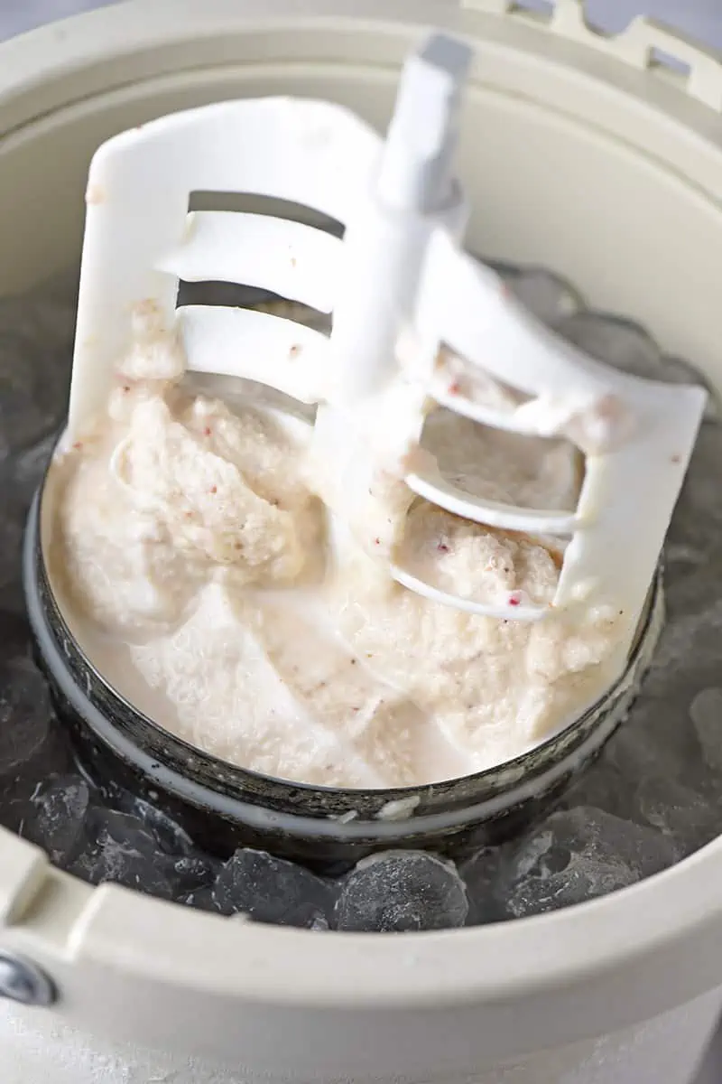 churning paddle in strawberry ice cream in old-fashioned ice cream maker