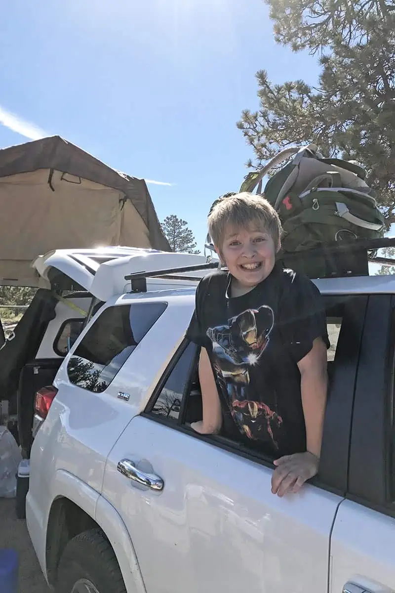 boy in white Toyota 4Runner packed up and ready to go camping with all the camping essentials