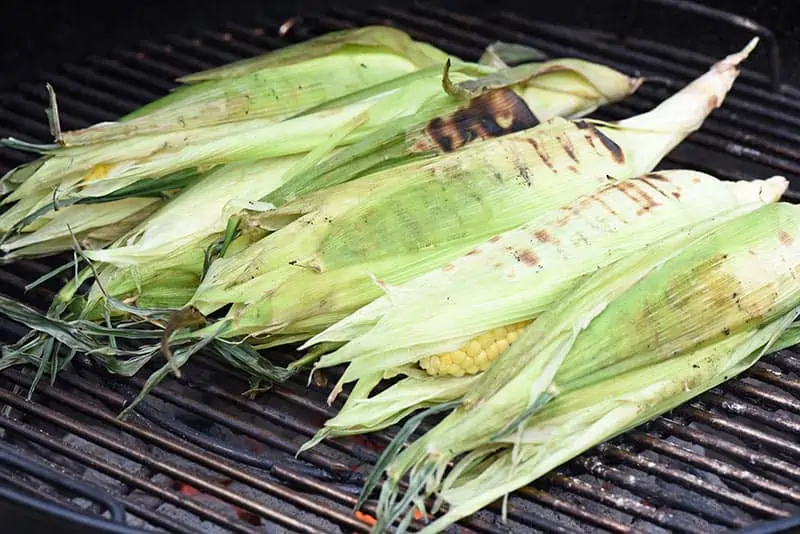 grilled sweet corn in the husk on a charcoal grill