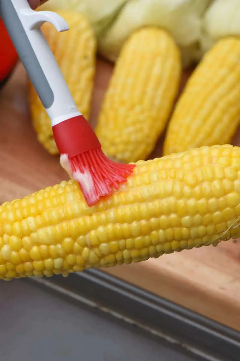 brushing grilled corn on the cob with honey butter
