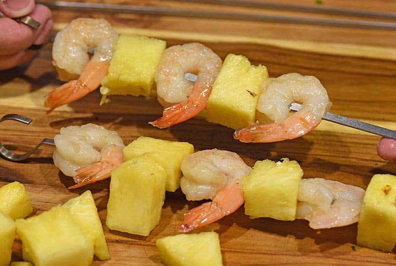 add marinated shrimp and pineapple chunks to skewers for shrimp kabobs
