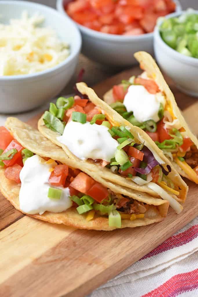 ground beef tacos with all the toppings on a wooden cutting board