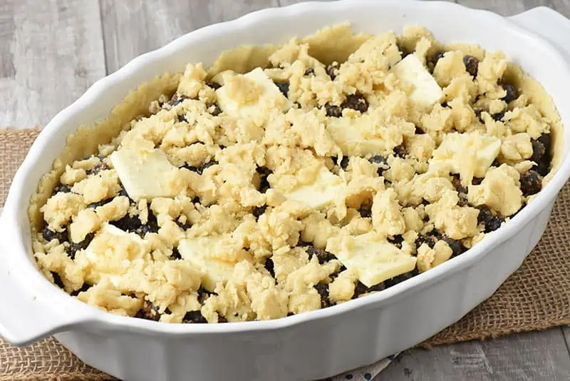 crumbled crust on top of blueberry cobbler in white baking dish