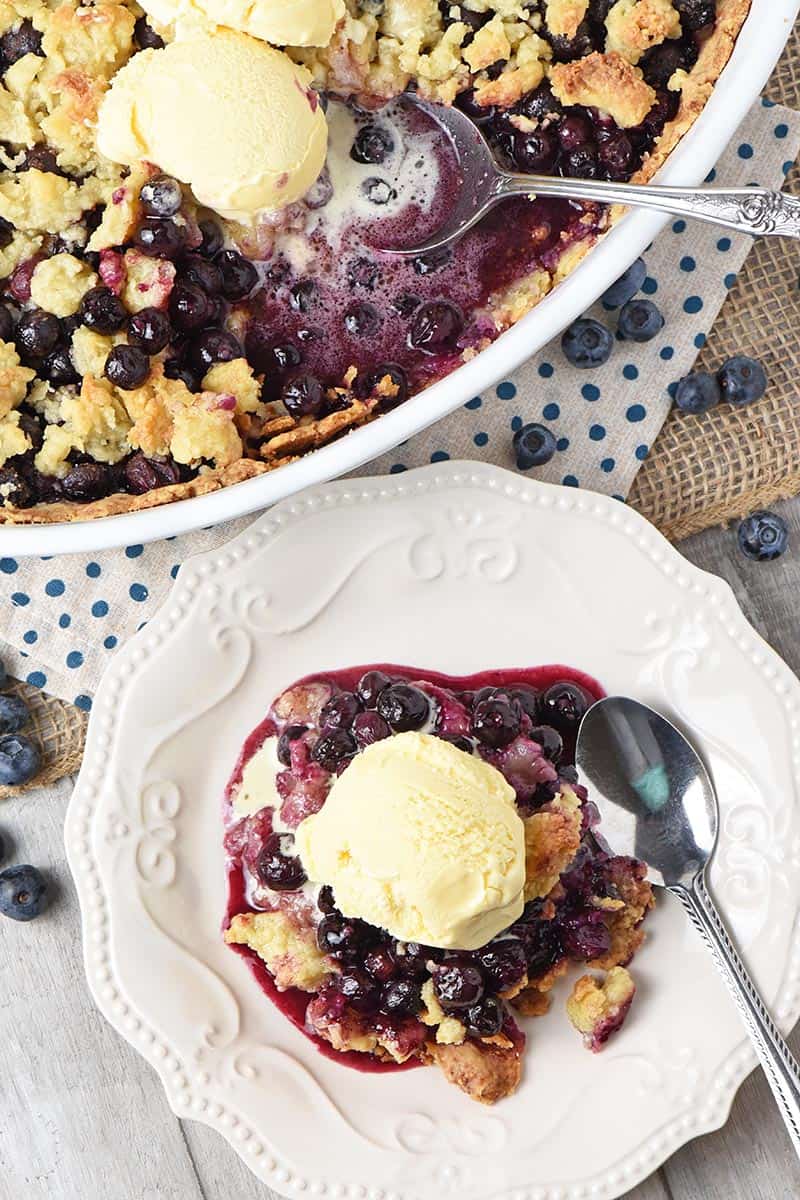 homemade blueberry cobbler recipe on white Pioneer Woman plate with scoop of vanilla ice cream