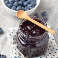blueberry filling for pie in a mason jar with a wooden spoon and fresh blueberries