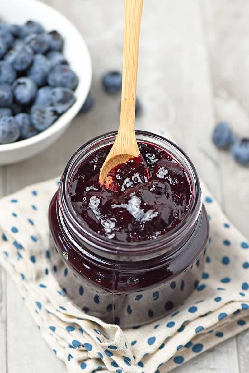 Wooden spoon in mason jar of freshly made blueberry filling for pie