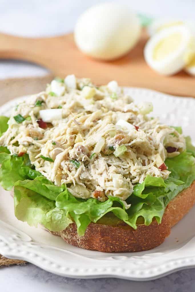 open-faced chicken salad recipe with eggs sandwich with lettuce on white plate