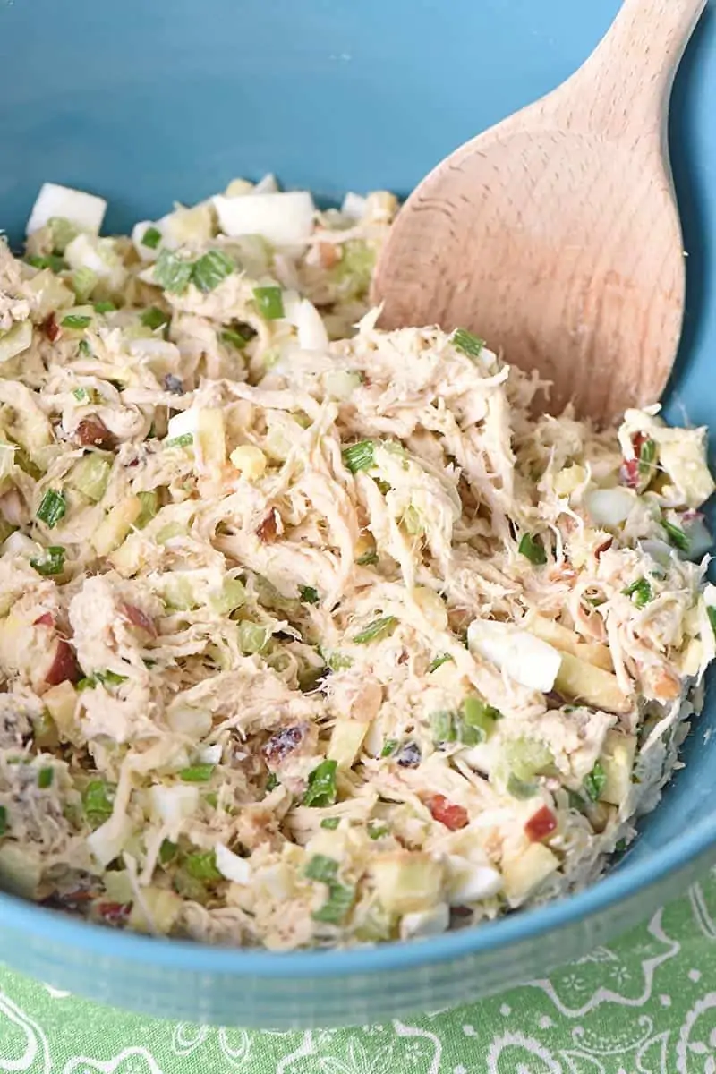 chicken salad with canned chicken or fresh cooked chicken mixed up in a blue bowl with a wooden spoon