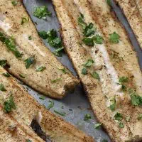 grilled fish fillets with cilantro on a baking sheet