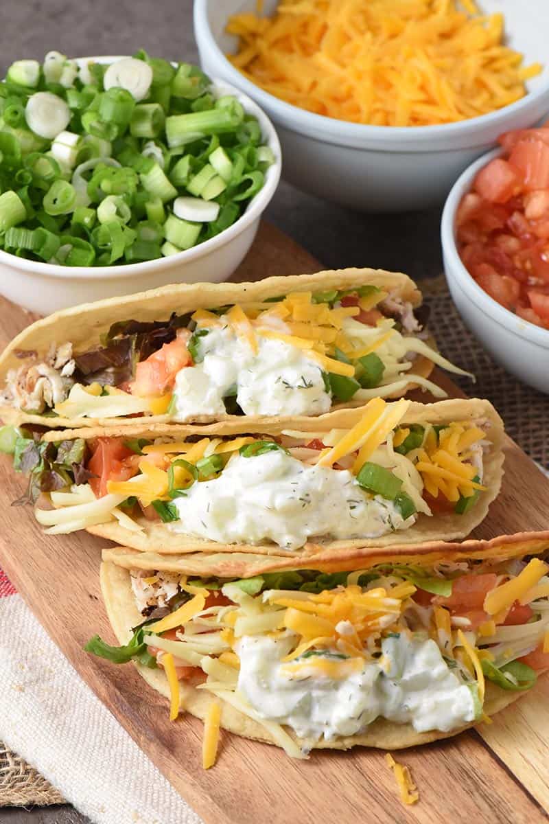 grilled fish tacos with a creamy tzatziki fish taco sauce on a wooden cutting board