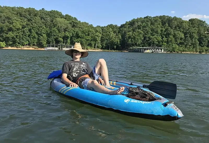 teen boy relaxing on inflatable kayak on Beaver Lake in Northwest Arkansas