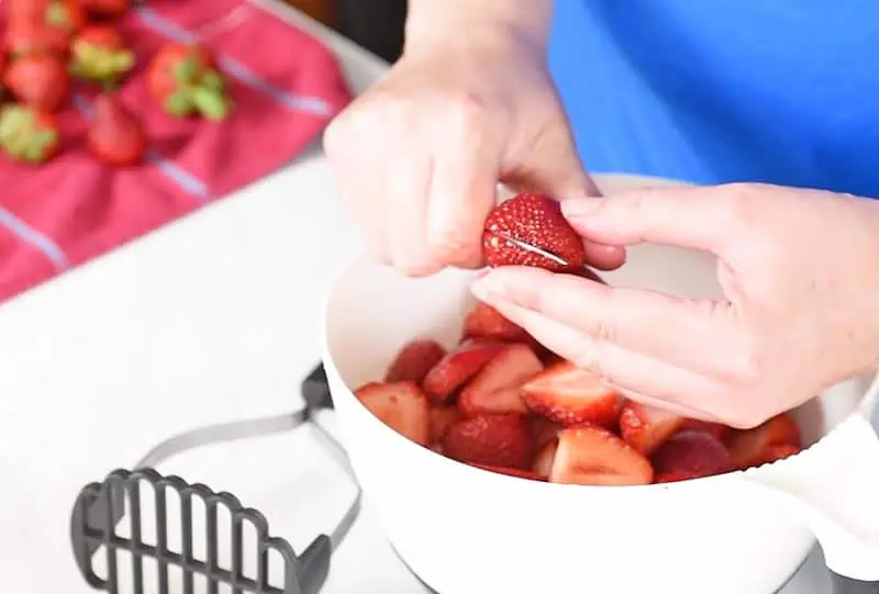 slicing strawberries in half for easy strawberry freezer jam
