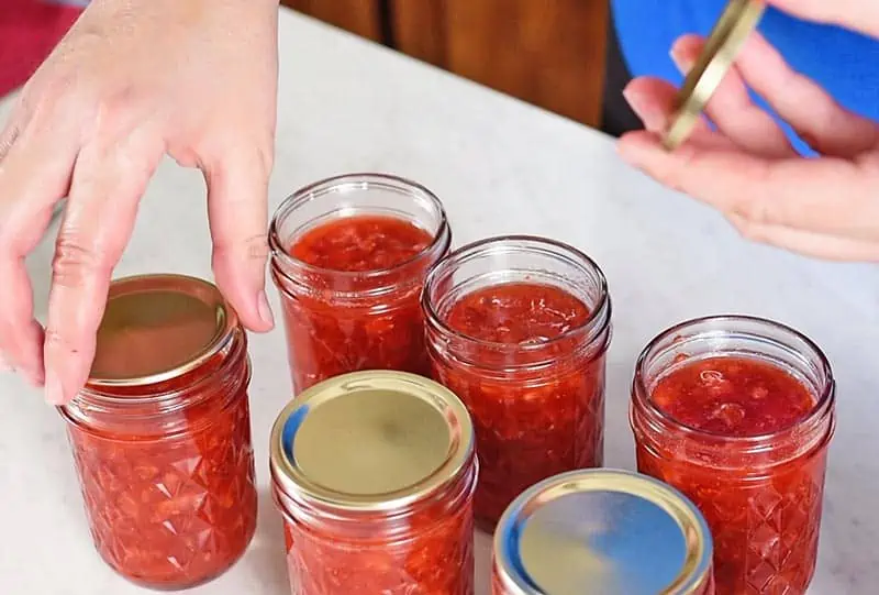 placing lids and bands on jars of fresh strawberry jam