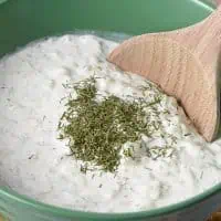easy recipe for tzatziki sauce in green bowl with wooden spoon