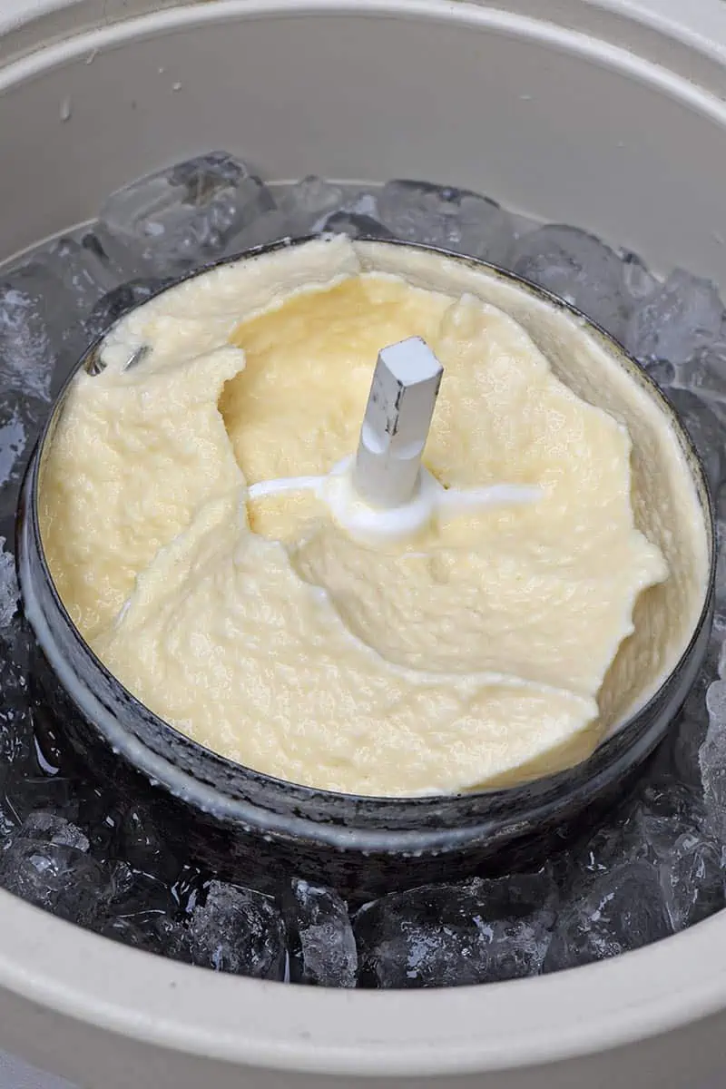 creamy vanilla ice cream in metal canister of ice cream maker set in ice