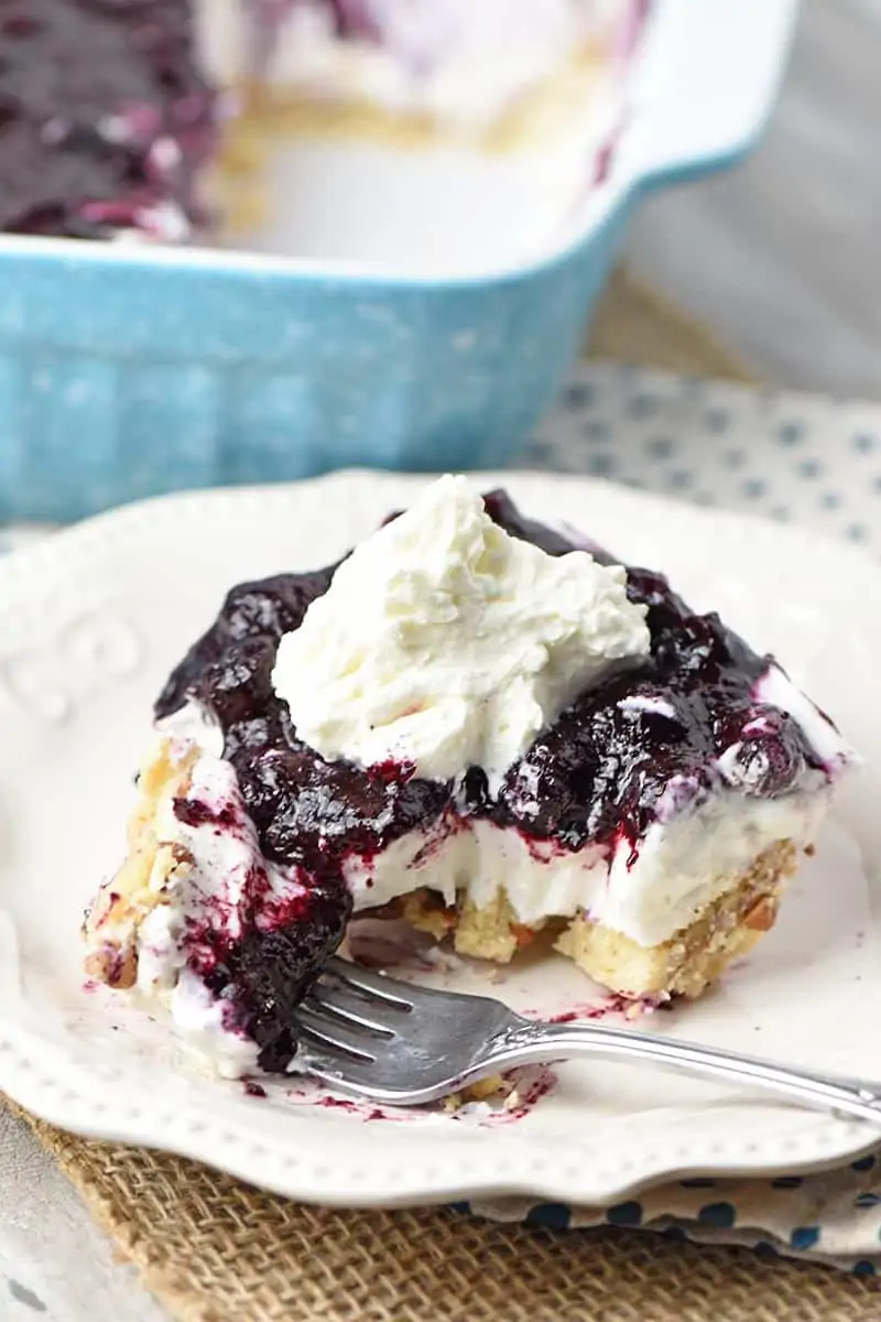 bite out of slice of no bake blueberry dessert on white plate