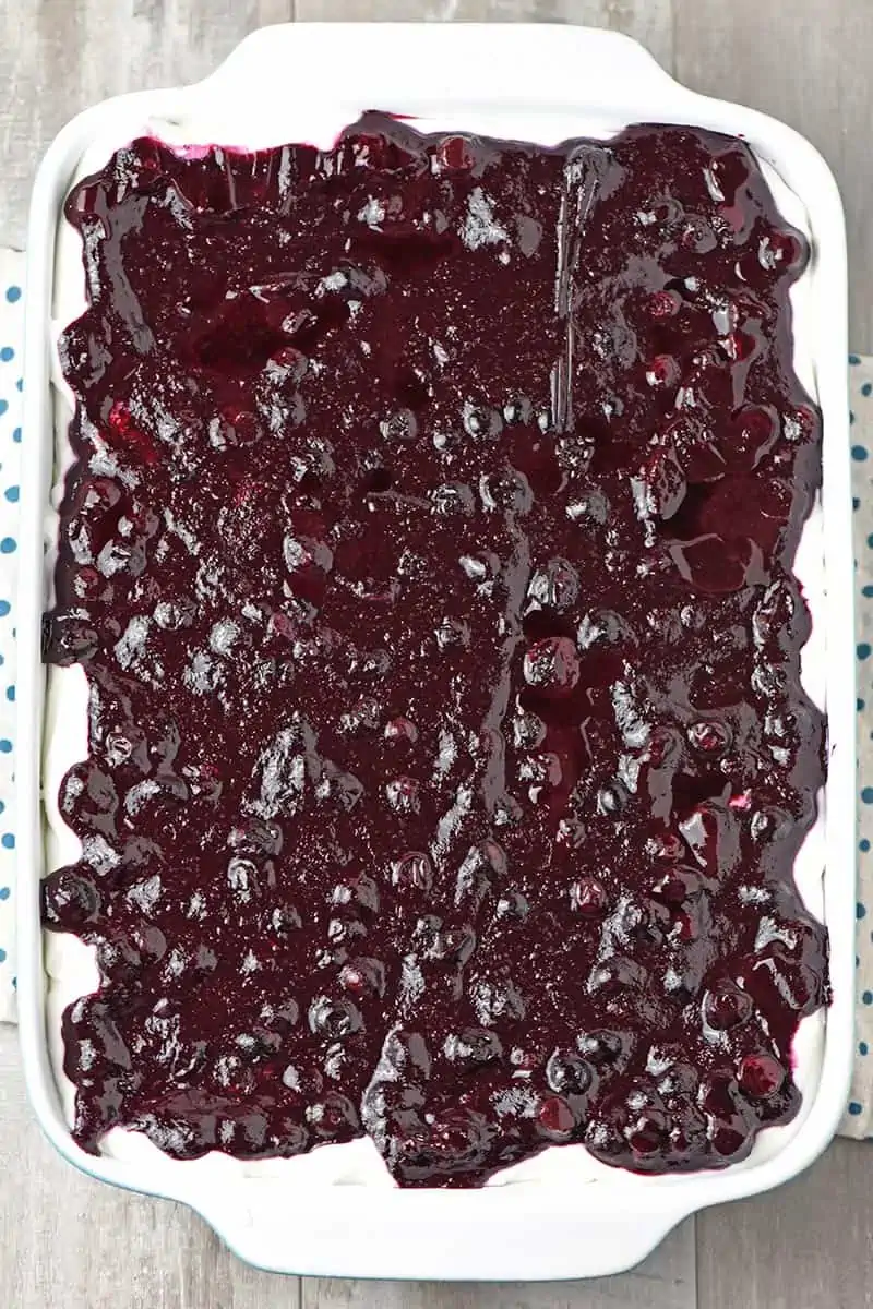 blueberry pie filling added to blueberry dessert in baking dish