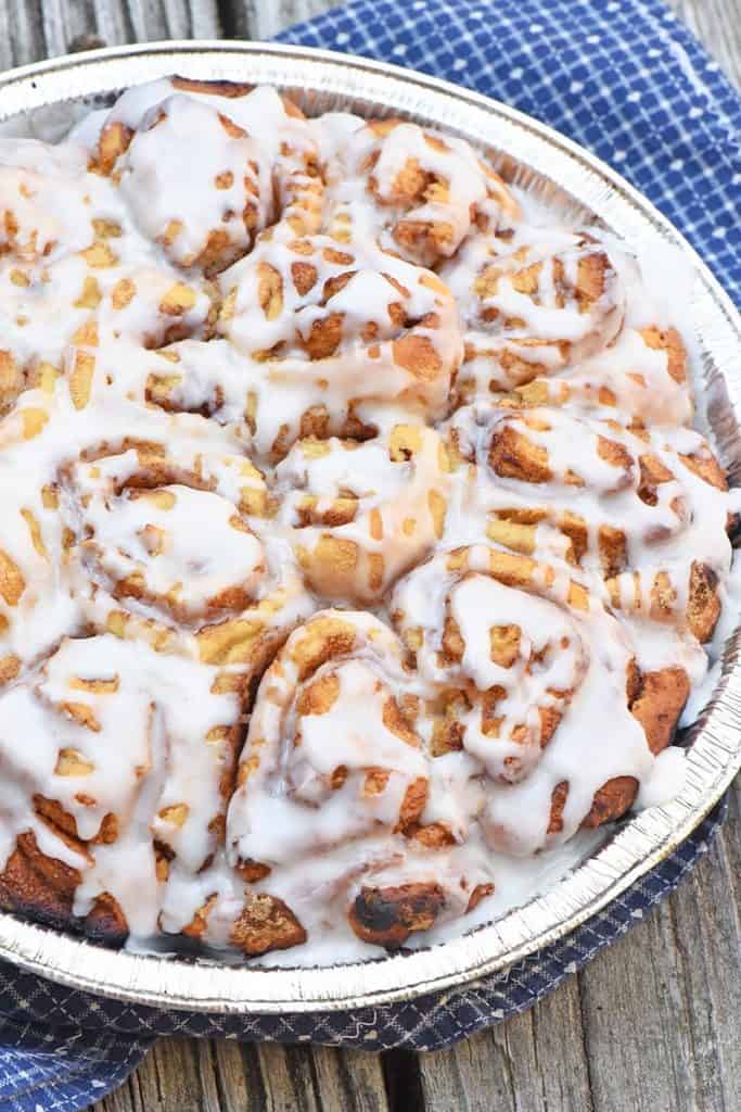campfire cinnamon rolls in foil pie plate on wood counter