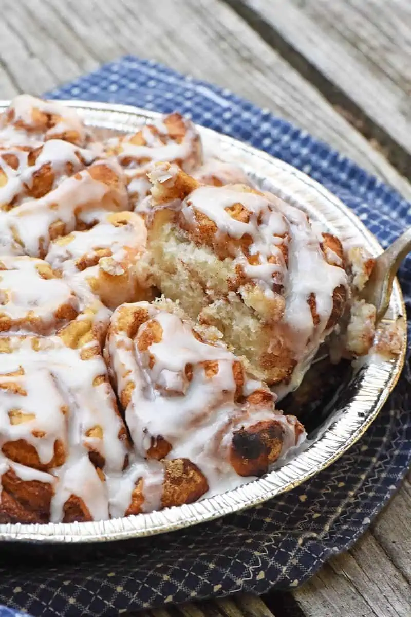 serving campfire cinnamon rolls on wood counter with blue linen cloth