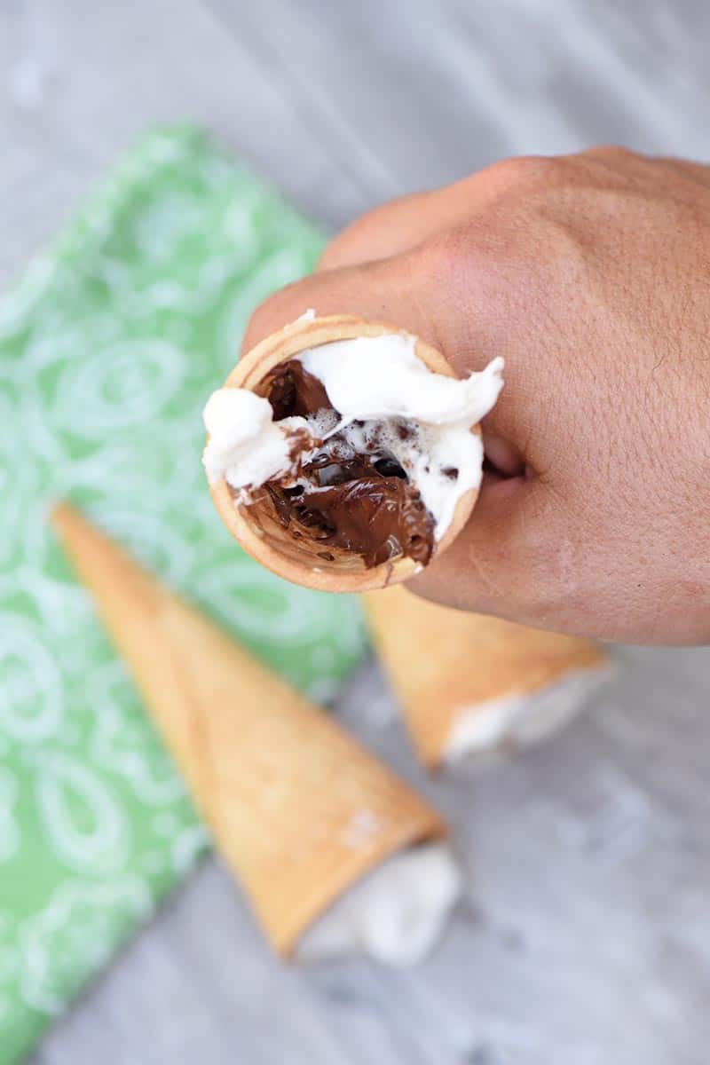 sugar cone s'mores after cooking on the grill, holding s'more in hand