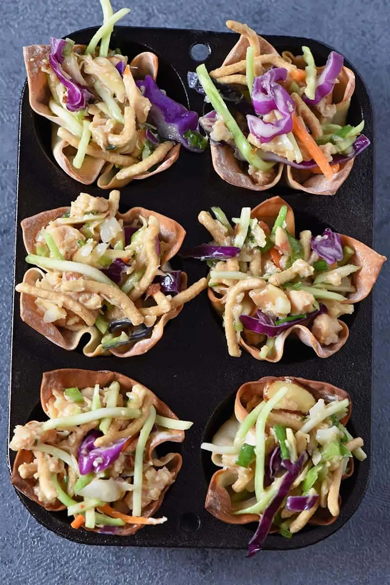 Asian chicken salad recipe made in baked wonton cups in a cast iron muffin tin