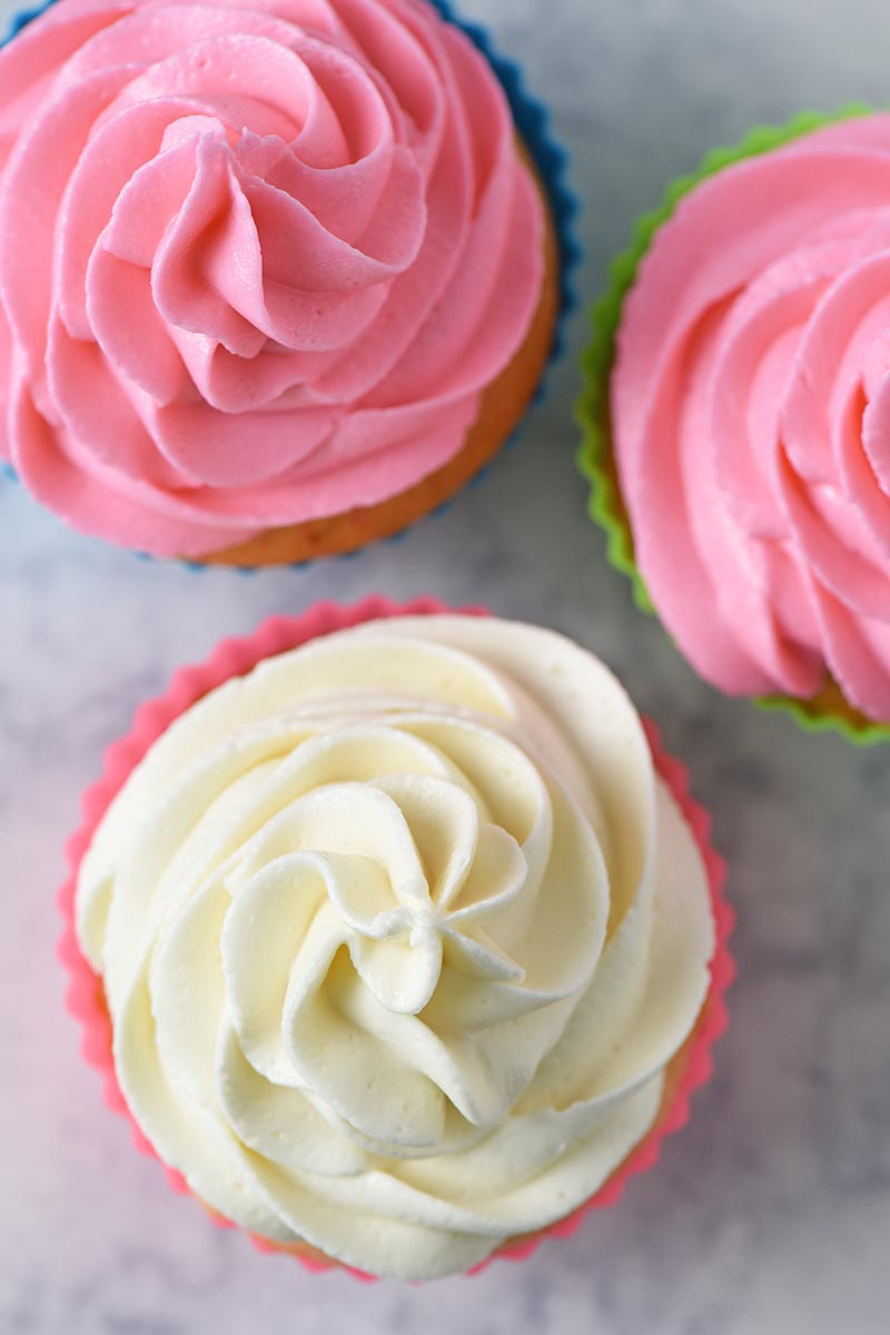best buttercream frosting for piping, buttercream icing for piping on cherry chip cupcakes on white marble countertop