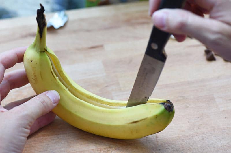 cutting a slit in a banana with a sharp knife to make banana s'mores