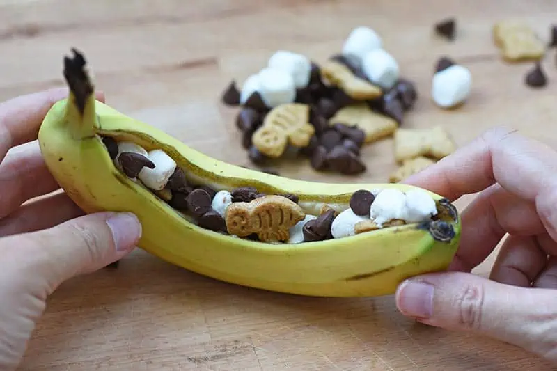 stuffing banana with chocolate, marshmallows, and graham crackers to make a banana s'more