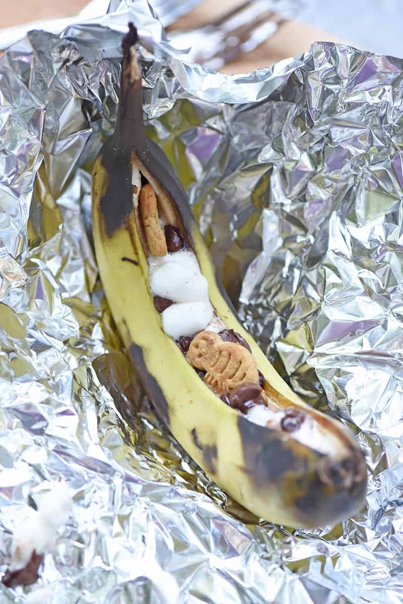unwrapping grilled banana s'mores from aluminum foil after cooking