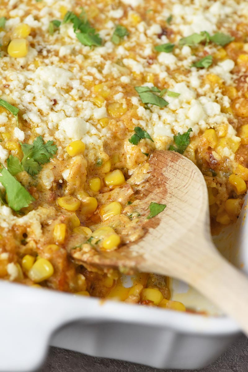 wooden spoon in Mexican corn casserole with cilantro on top