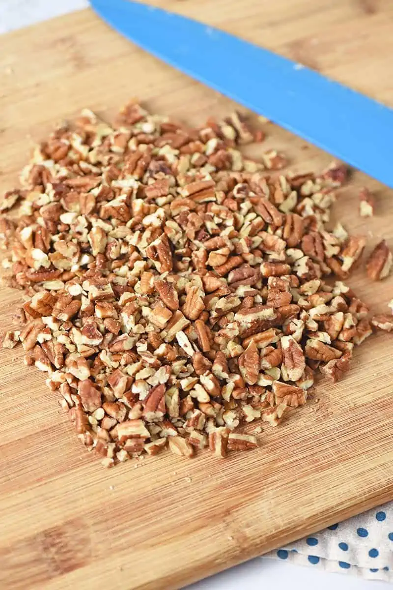 chopped pecans for pie crust recipe on cutting board with knife