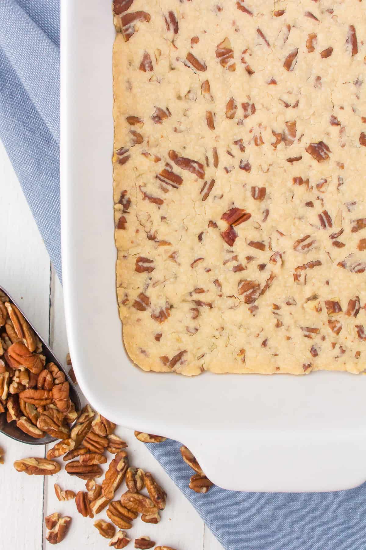 closeup photo showing a pecan pie crust for layered desserts pressed out into a white 9x13 baking pan