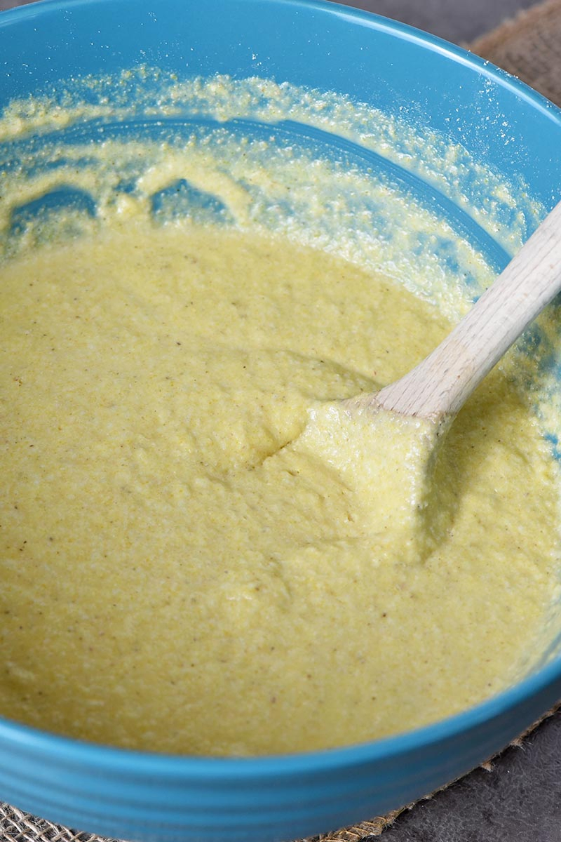 buttermilk cornbread batter with wooden spoon in blue mixing bowl