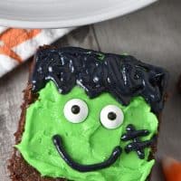 Frankenstein brownies decorated with frosting and candy eyeballs on wood countertop with candy corn