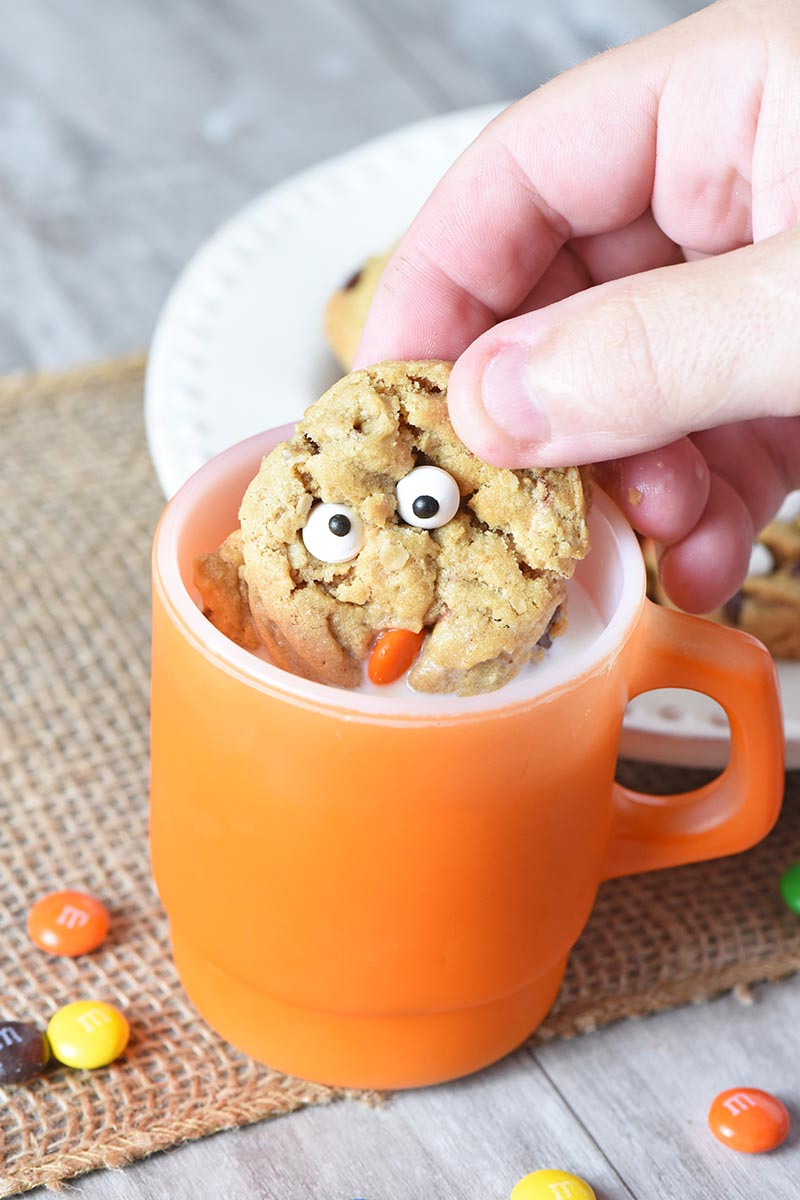 dunking monster cookies in milk in orange Fire King mug