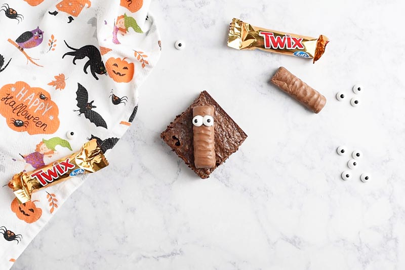 add candy eyeballs to Twix bar for mummy Halloween brownies