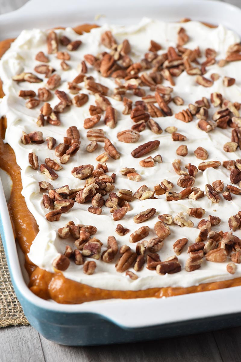 no bake pumpkin dessert layered in blue baking dish with pecans on top