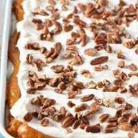 no bake pumpkin dessert with whipped cream and pecans on top in blue baking dish