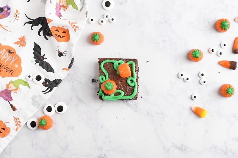 decorating pumpkin patch Halloween brownies with Brach's Mellowcreme Pumpkins and green icing for a quick and easy Halloween dessert