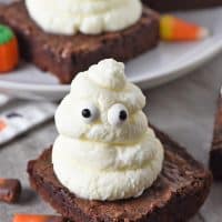 ghost halloween brownies made with whipped cream and candy eyeballs, on a countertop with candy corn and candy corn pumpkins