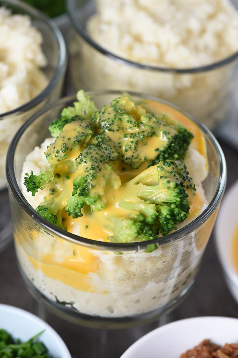 broccoli and cheese sauce on mashed potato in small glass trifle dish