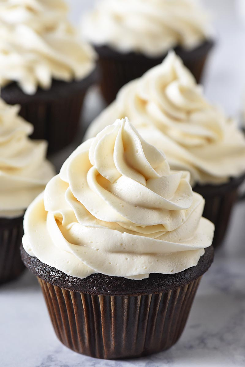 fluffy and moist chocolate cupcakes with butterbeer buttercream frosting on white marble countertop