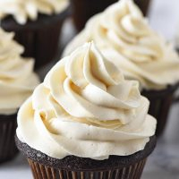 fluffy butterbeer buttercream frosting on dark chocolate cupcakes on white marble countertop