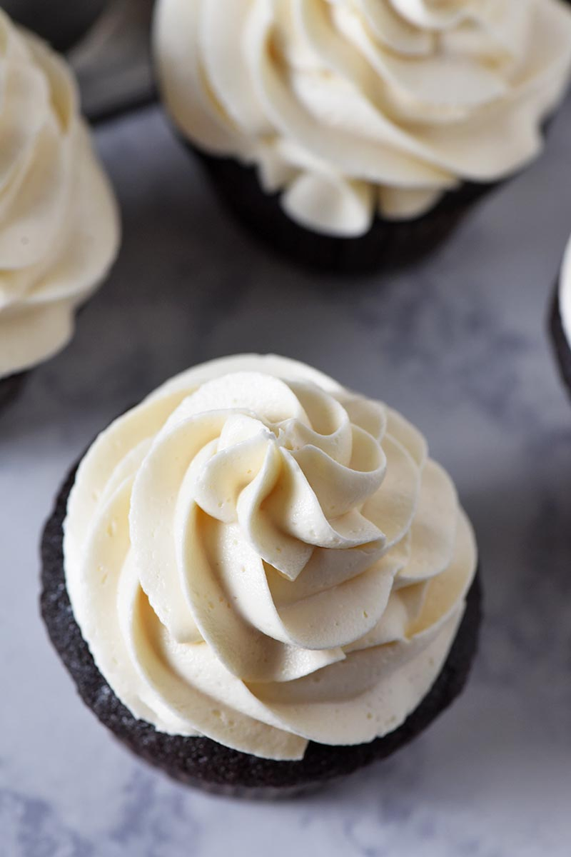 swirl of butterbeer buttercream frosting on dark chocolate cupcakes on white marble counter